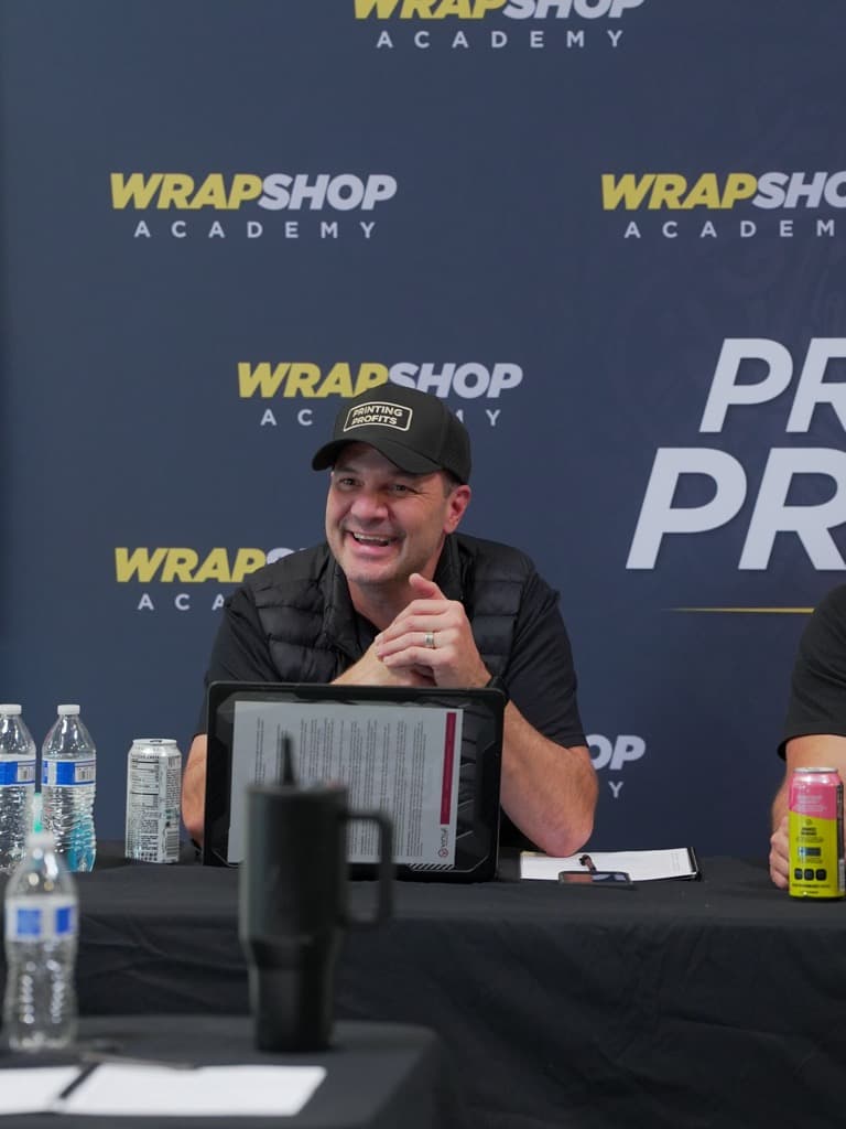 A cofounder grinning at the camera from behind the Wrap Shop Academy panel table