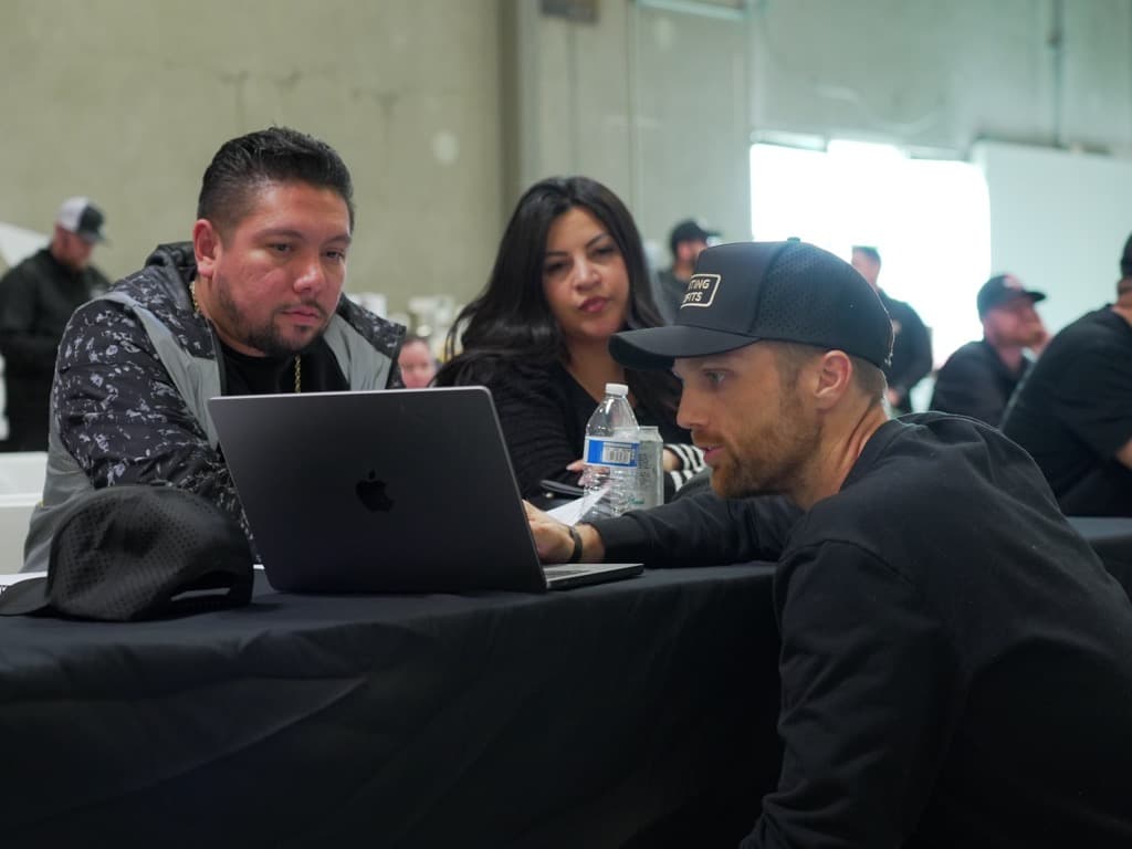 Cofounder reviewing work on a laptop with two wrap shop owners during the workshop